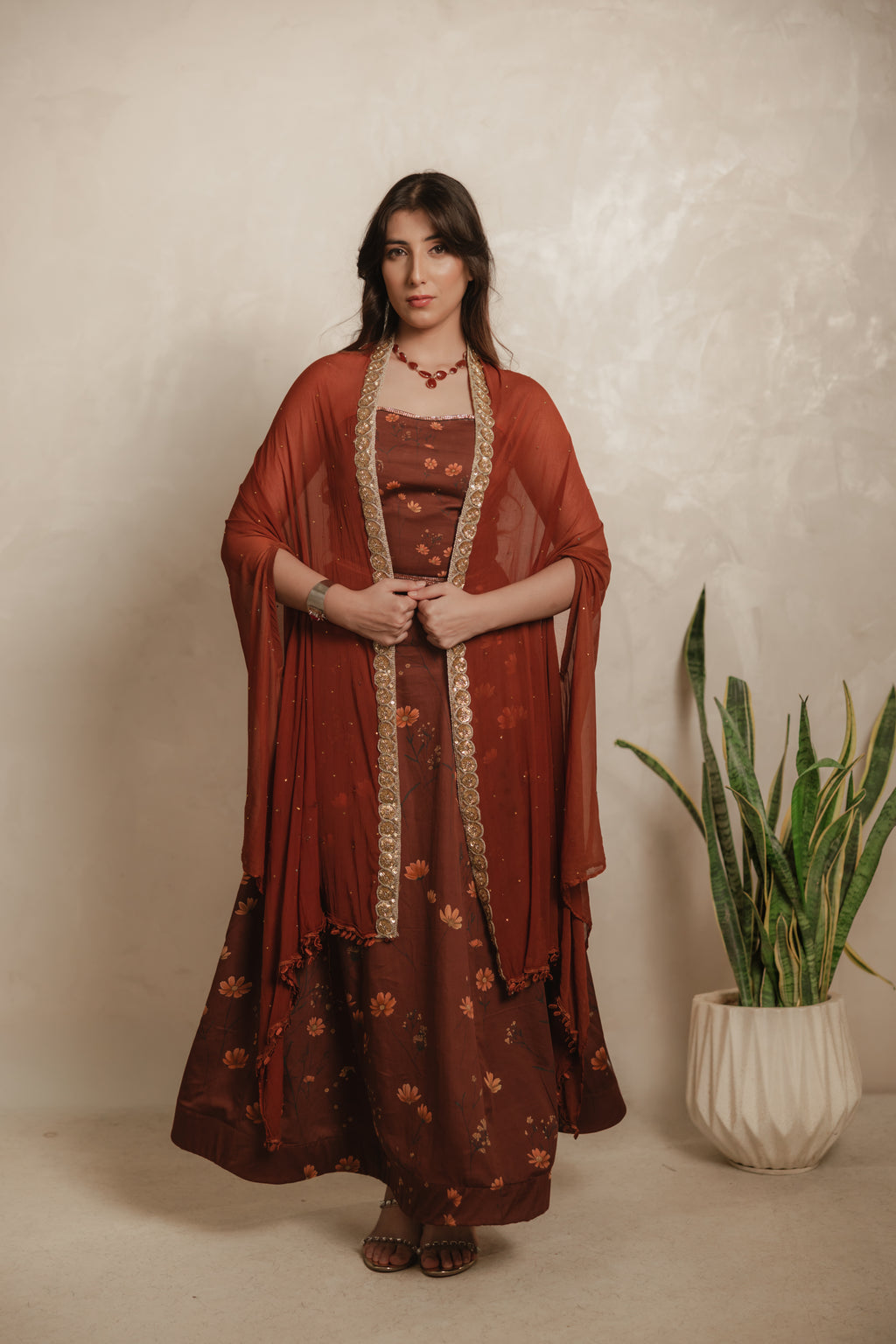 Sthira Calendula gown in vegan silk, rust-brown botanical print, full length front, cape held at the waist