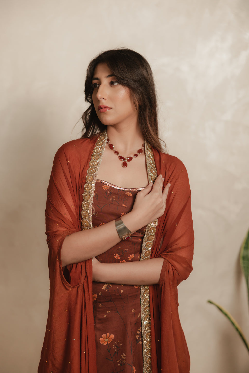Sthira Calendula gown in vegan silk, rust-brown botanical print, closer view with cape dupatta, hand at chest