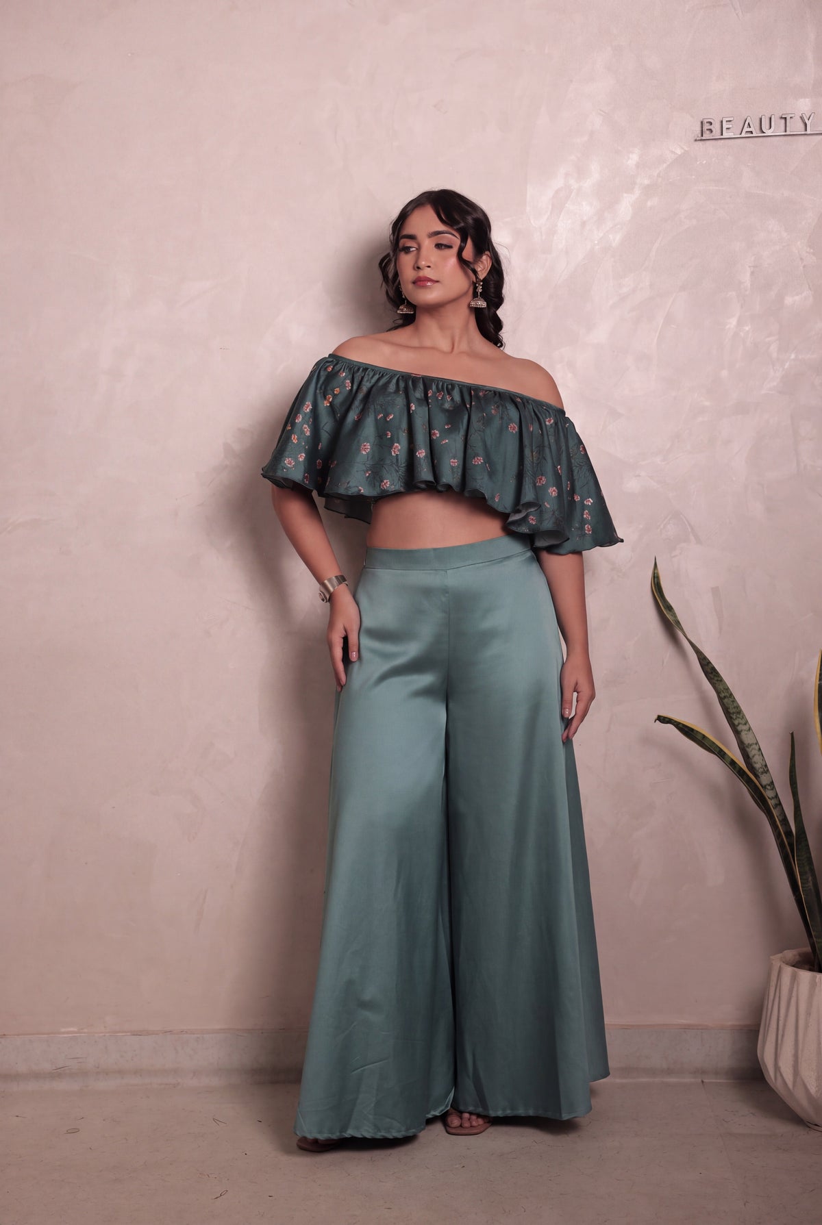 Sthira Bluebell co-ord set in vegan silk, deep teal ruffle blouse and smooth satin trousers, full length, gaze to the side